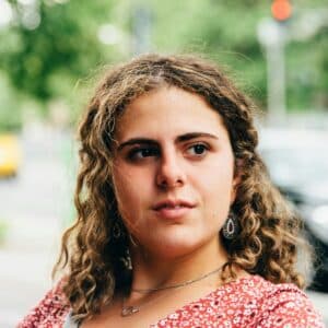 Headshot portrait of confident beautiful young woman with curly hair.