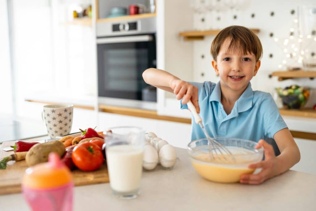 A happy child in Calgary preparing a meal from the Coaching Program in NutriPOM's Holistic Nutrition Programs.