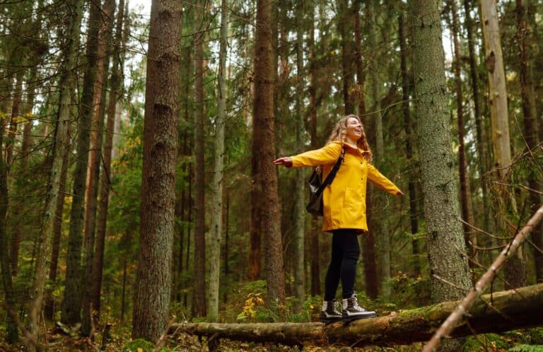 Happy tourist with backpack walking on log in forest, balancing: healthy lifestyle, harmony concept